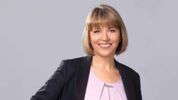 Porträt von Beate Schlupp (Landtag MV). Sie lächelt freundlich in die Kamera, trägt einen dunklen Blazer über einem rosa Oberteil und steht vor einem schlichten, grauen Hintergrund.