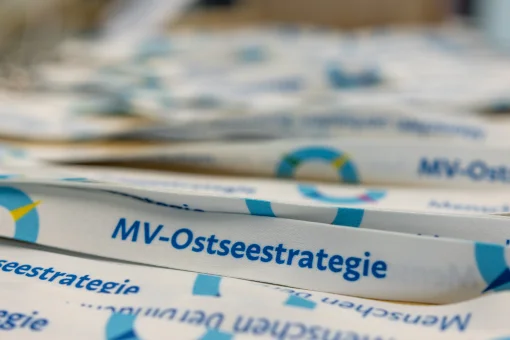 Eine Nahaufnahme mehrerer weißer Schlüsselbänder (Lanyards) mit dem Aufdruck „MV-Ostseestrategie“ und dem passenden Logo. Das vorderste Band ist scharf fokussiert, während die Bänder im Hintergrund unscharf verschwimmen.